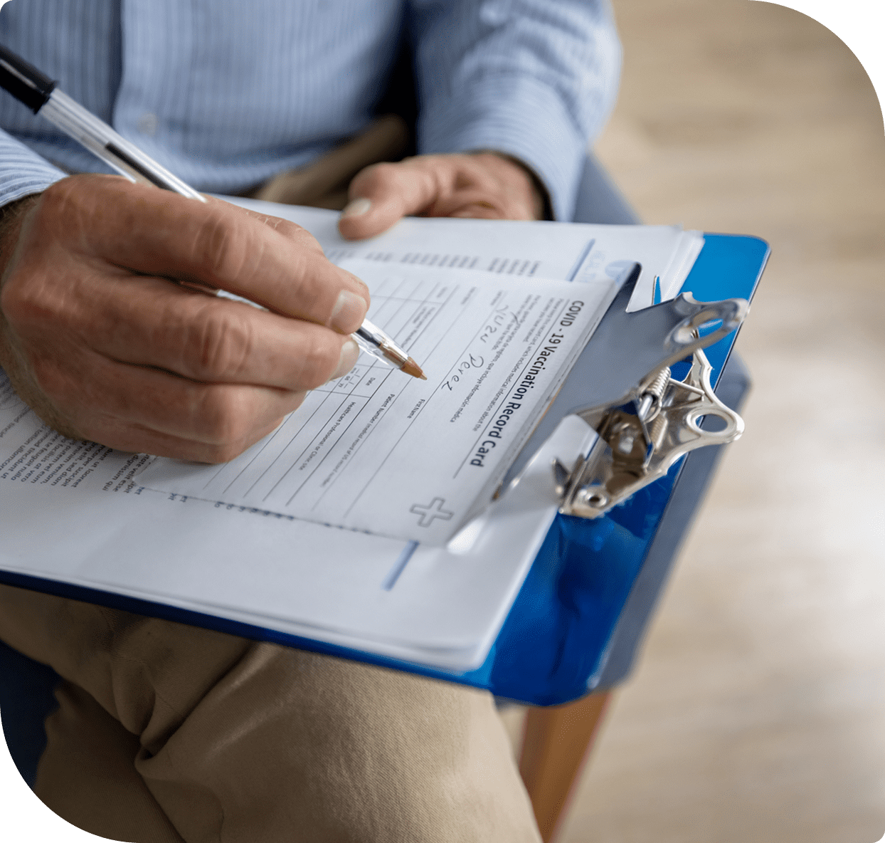 Person filling out medical form on clipboard.