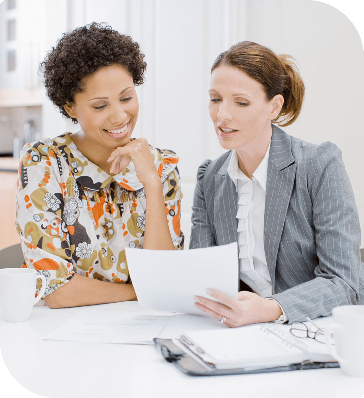 Two women reviewing documents at desk.